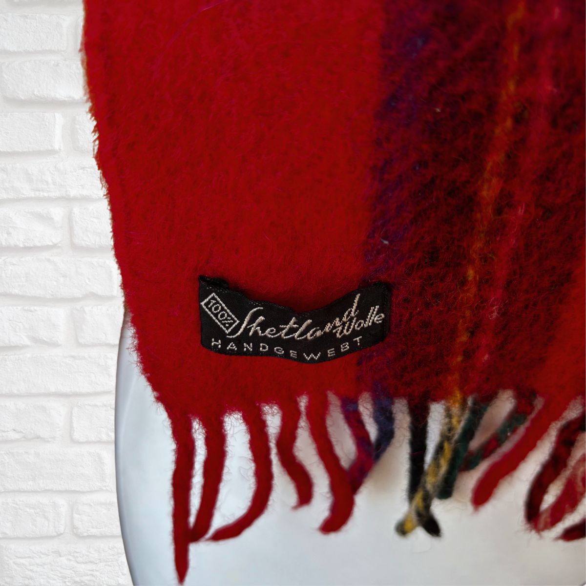 Red scarf with a label on a white brick wall background