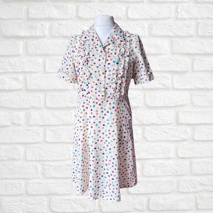 Short-sleeve dress with colorful polka dot pattern on a mannequin against a white brick wall.