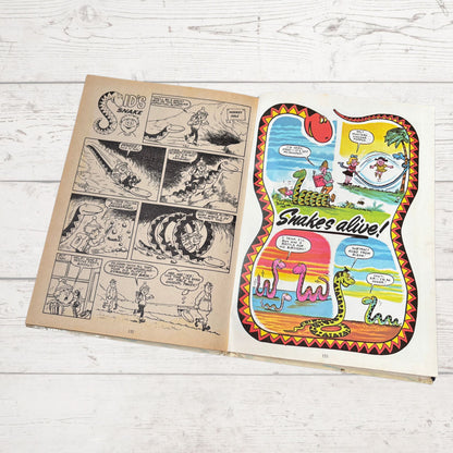 Open comic book with snake-themed illustration on a wooden surface