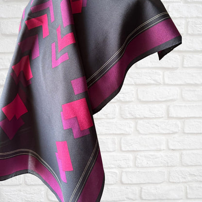 Scarf with pink and purple geometric pattern on a white brick wall background