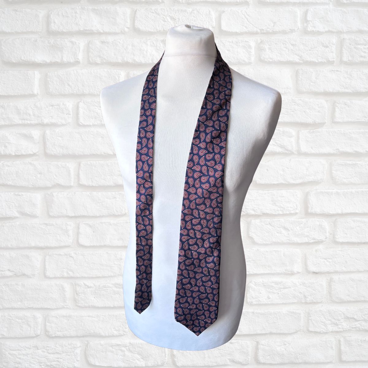 Navy and Red Paisley Silk Vintage Tie On a white brick background 