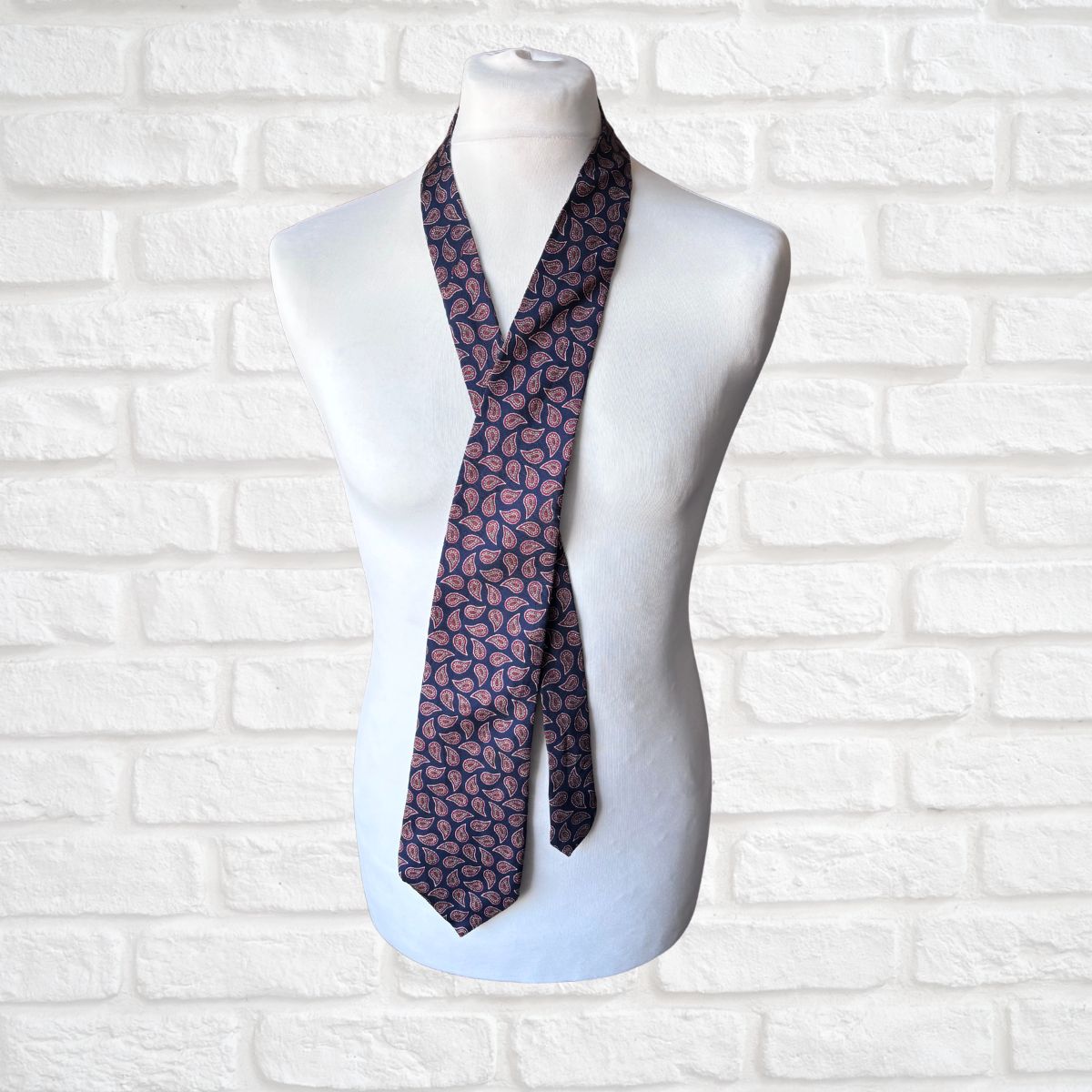 Navy and Red Paisley Silk Vintage Tie On a white brick background 