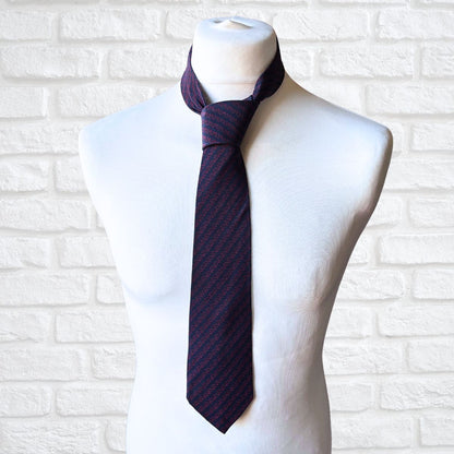 Navy printed tie on a mannequin against a white brick wall background