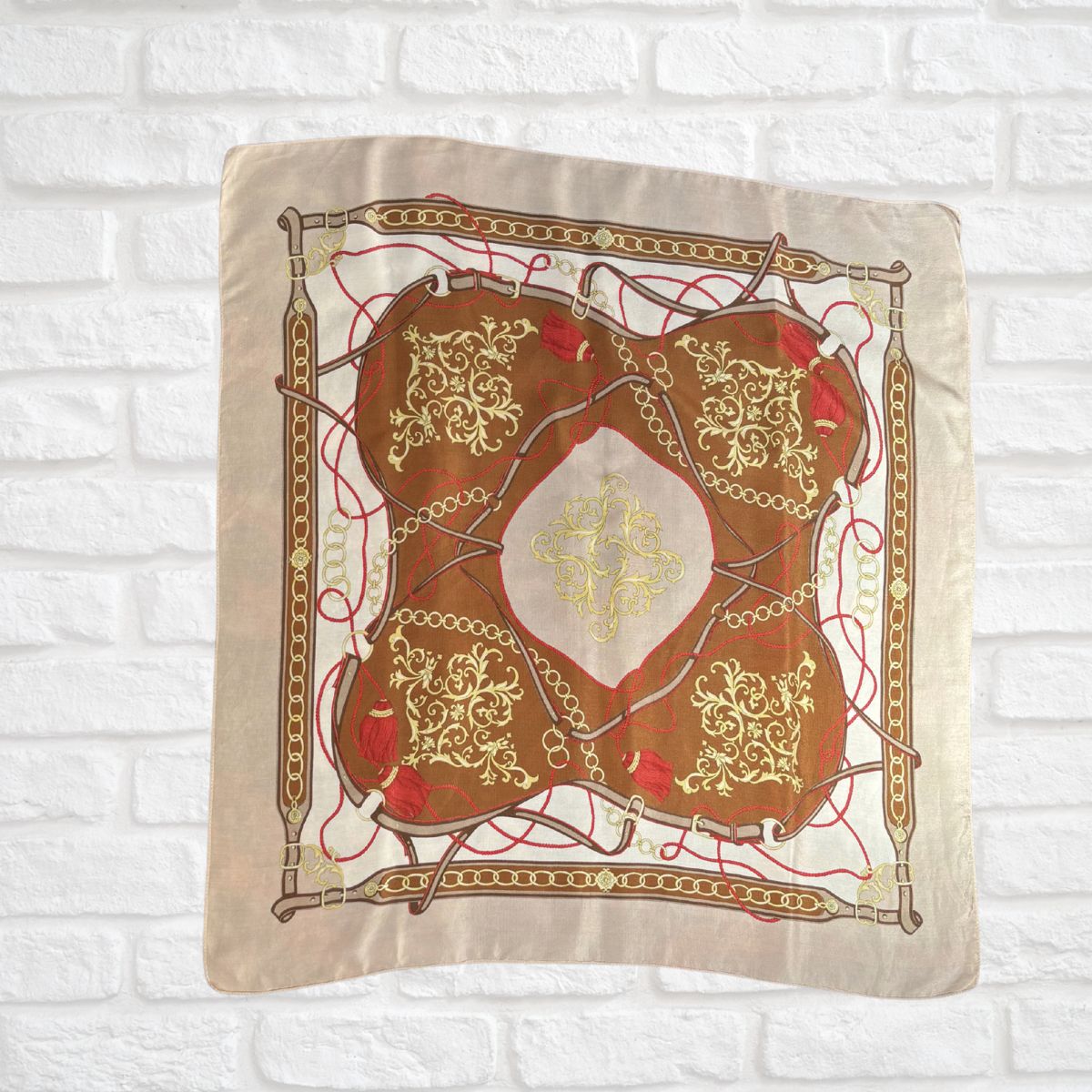 Decorative fabric with intricate gold and red patterns on a white brick wall background