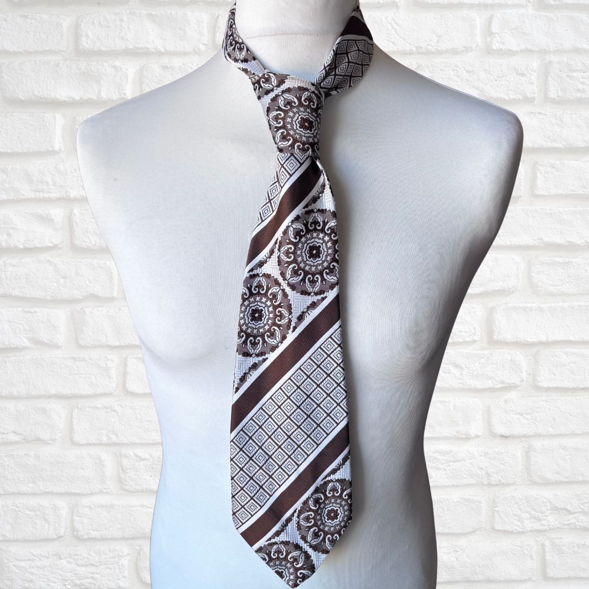 Patterned tie on a mannequin against a white brick wall background