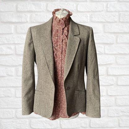 Brown blazer and patterned shirt on a mannequin against a white brick wall.