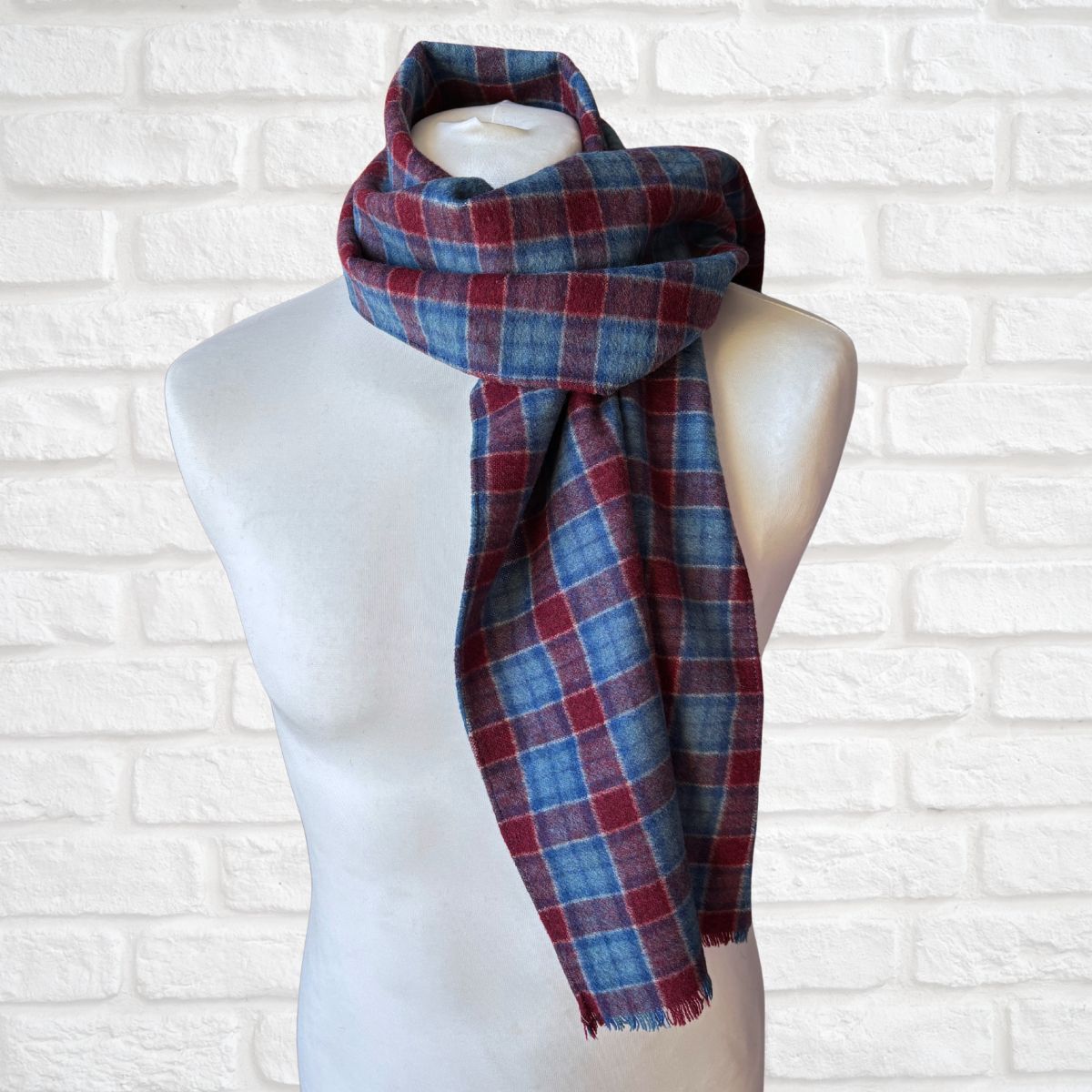 Plaid scarf on a mannequin against a white brick wall