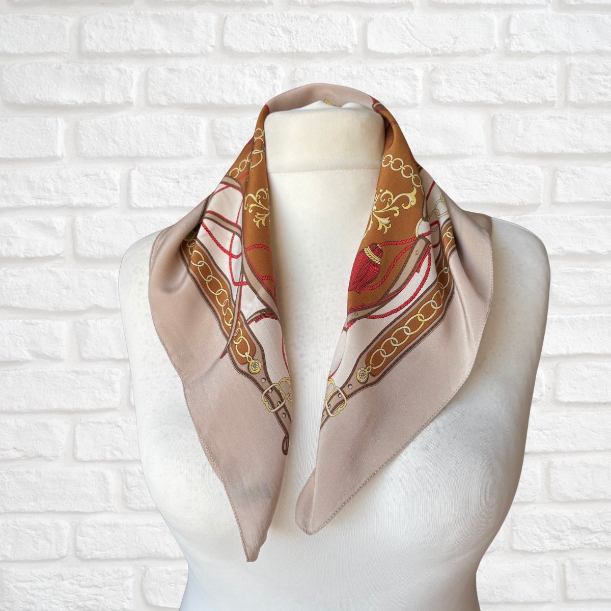 Decorative scarf on a mannequin against a white brick wall background