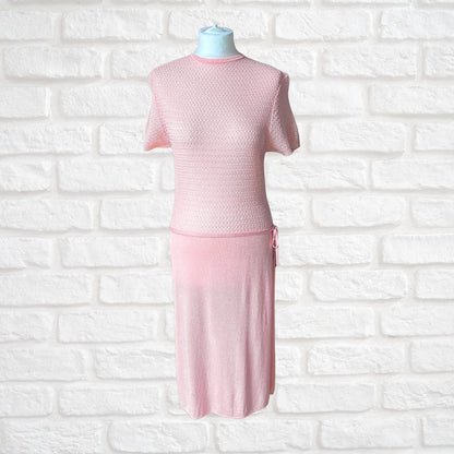 A light pink knit  dress displayed on a mannequin torso against a white brick wall background.
