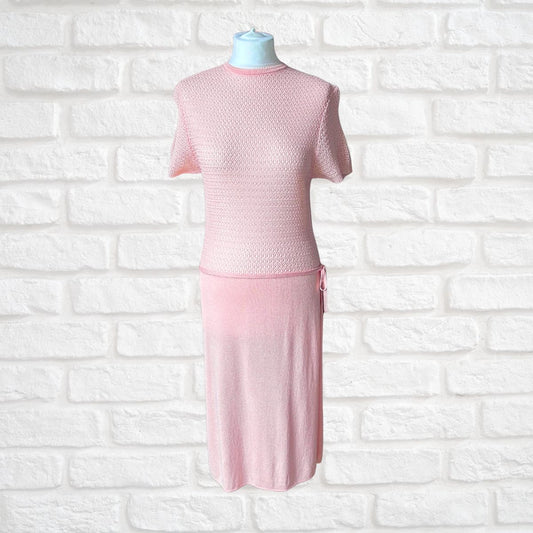 A light pink knit  dress displayed on a mannequin torso against a white brick wall background.