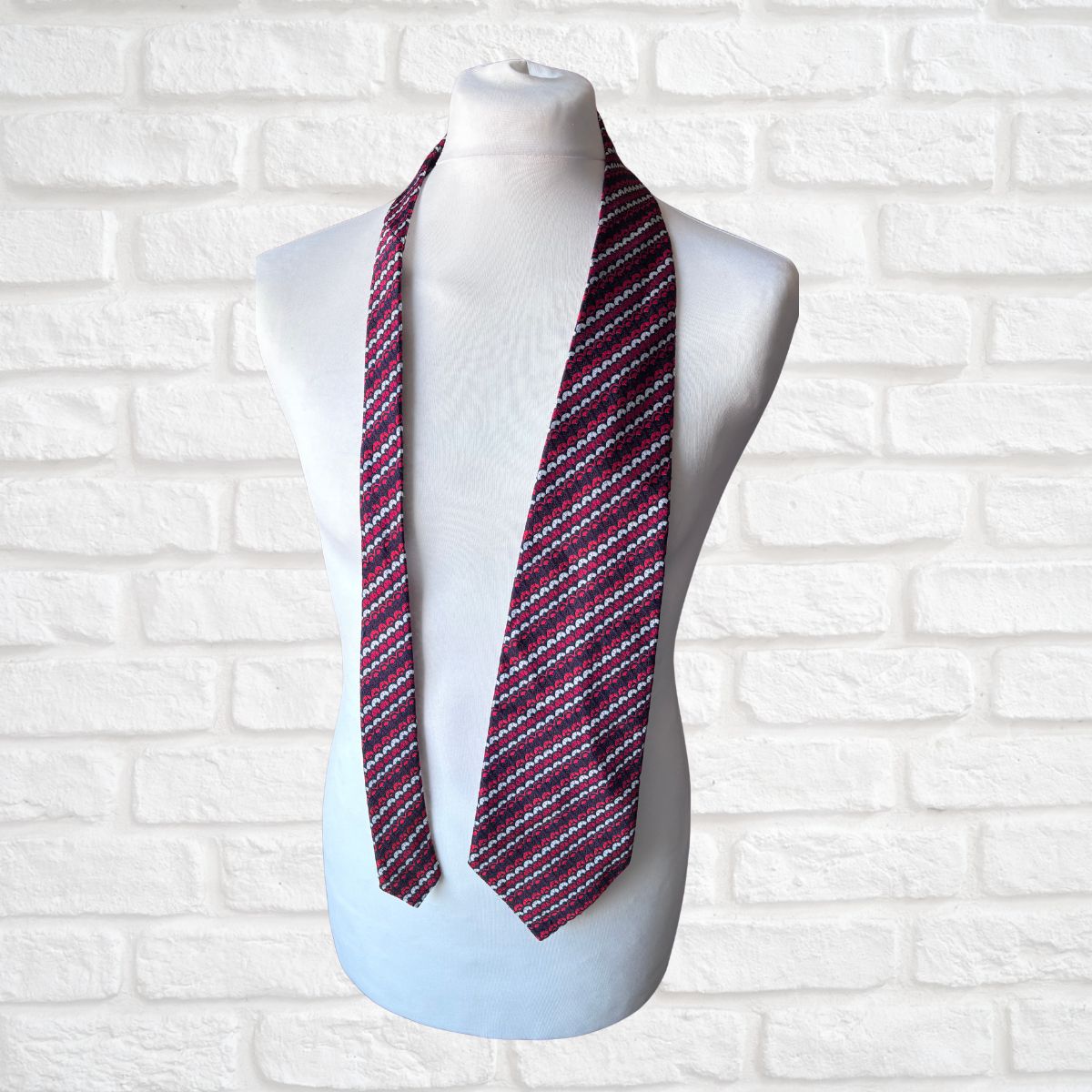 Striped scarf on a mannequin against a white brick wall background