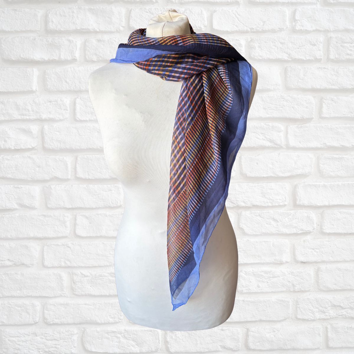 Colourful silk scarf on a mannequin against a white brick wall background