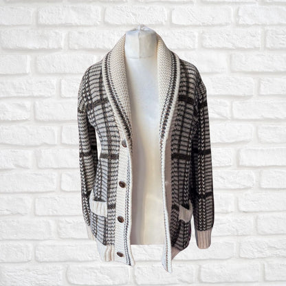 A brown and cream knit cardigan sweater displayed on a white mannequin torso against a white brick wall background.