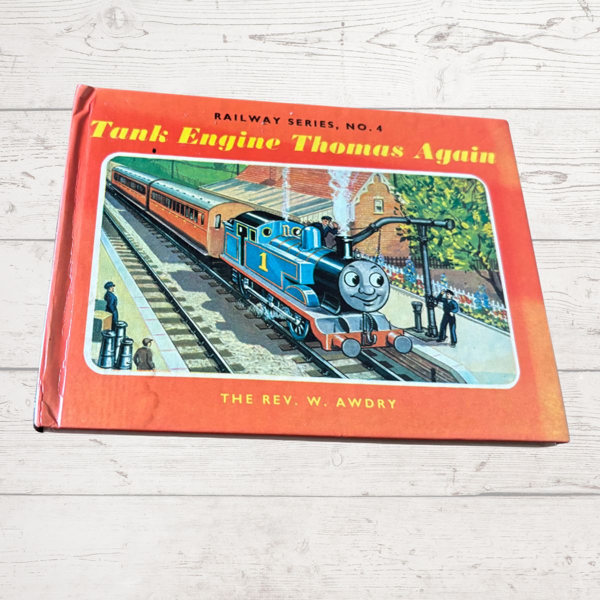 Book titled 'Tank Engine Thomas Again' by W. Awdry on a wooden surface