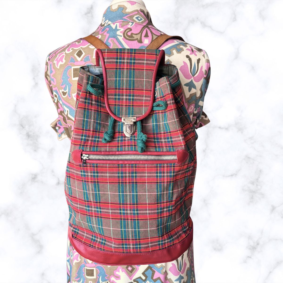 Plaid backpack on a mannequin with a colorful patterned sleeve.