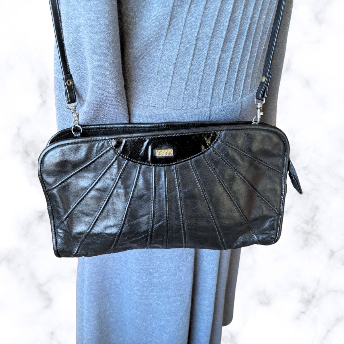 Black leather handbag with a textured surface on a light gray background