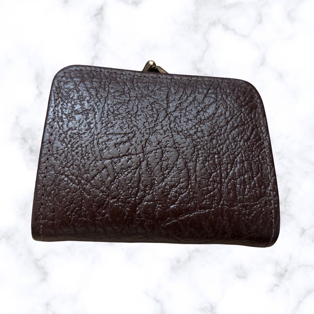 Brown leather clutch bag on a white marble background