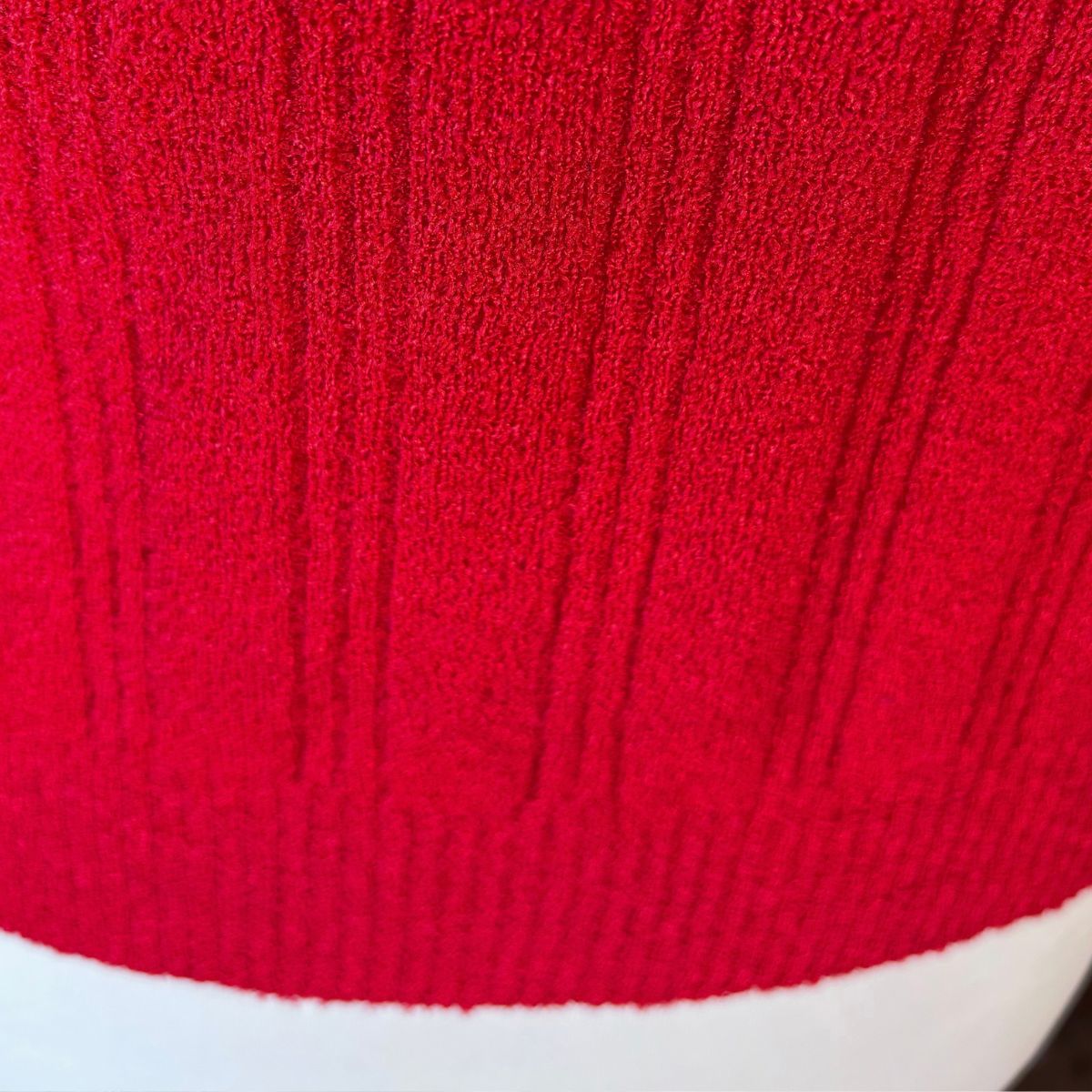 A close-up of a bright red ribbed knit fabric, showing the detailed vertical texture and pattern.