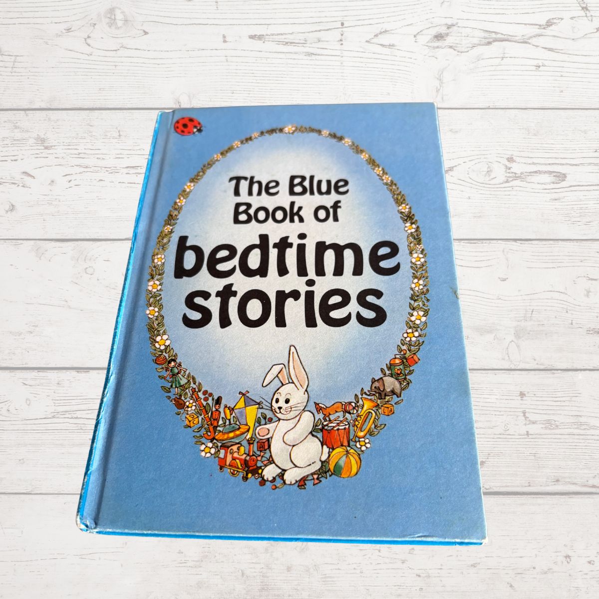 The Blue Book of Bedtime Stories paperback book on a white wooden background.