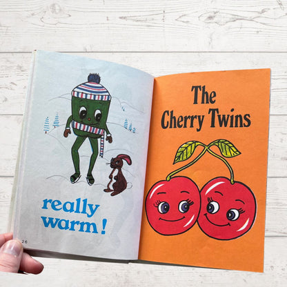 Open book showing the title page with a cartoon cherry and pepper characters on an orange background.