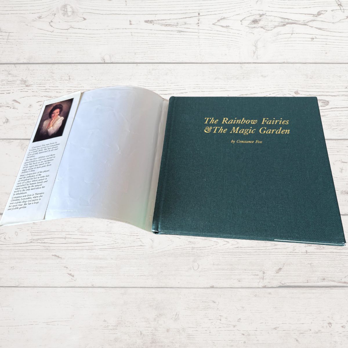 Open book with a green cover on a light wooden surface