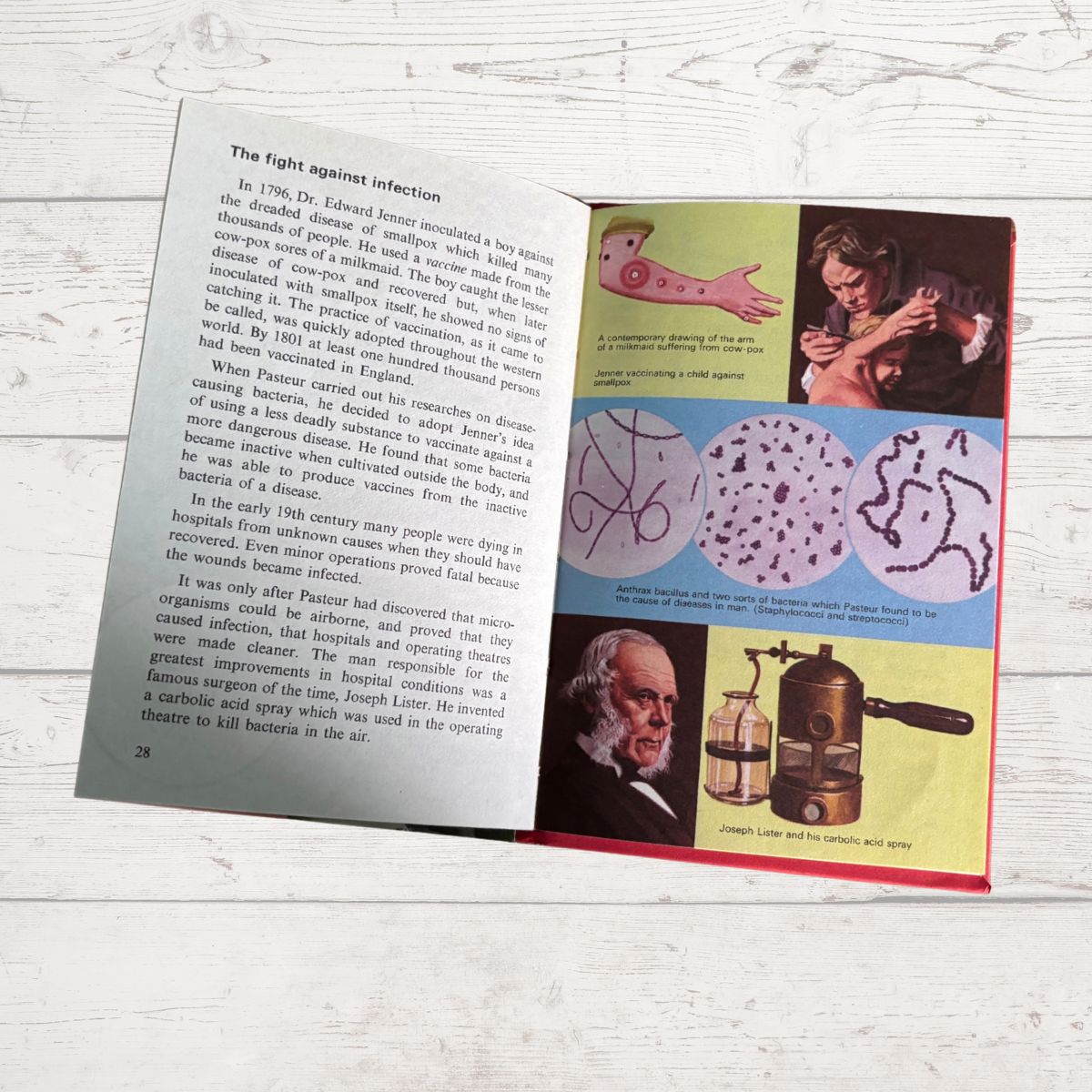 An open book spread showing printed pages with text and colorful medical illustrations, photographed on a light wood surface.