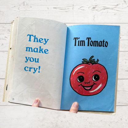Open book with a cartoon tomato character and text on a wooden surface