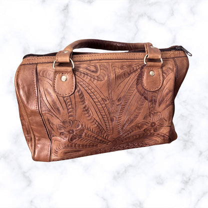Brown leather handbag with floral embossing on a white background