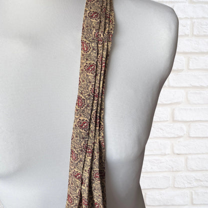 Patterned cravat draped over a mannequin against a white brick wall.