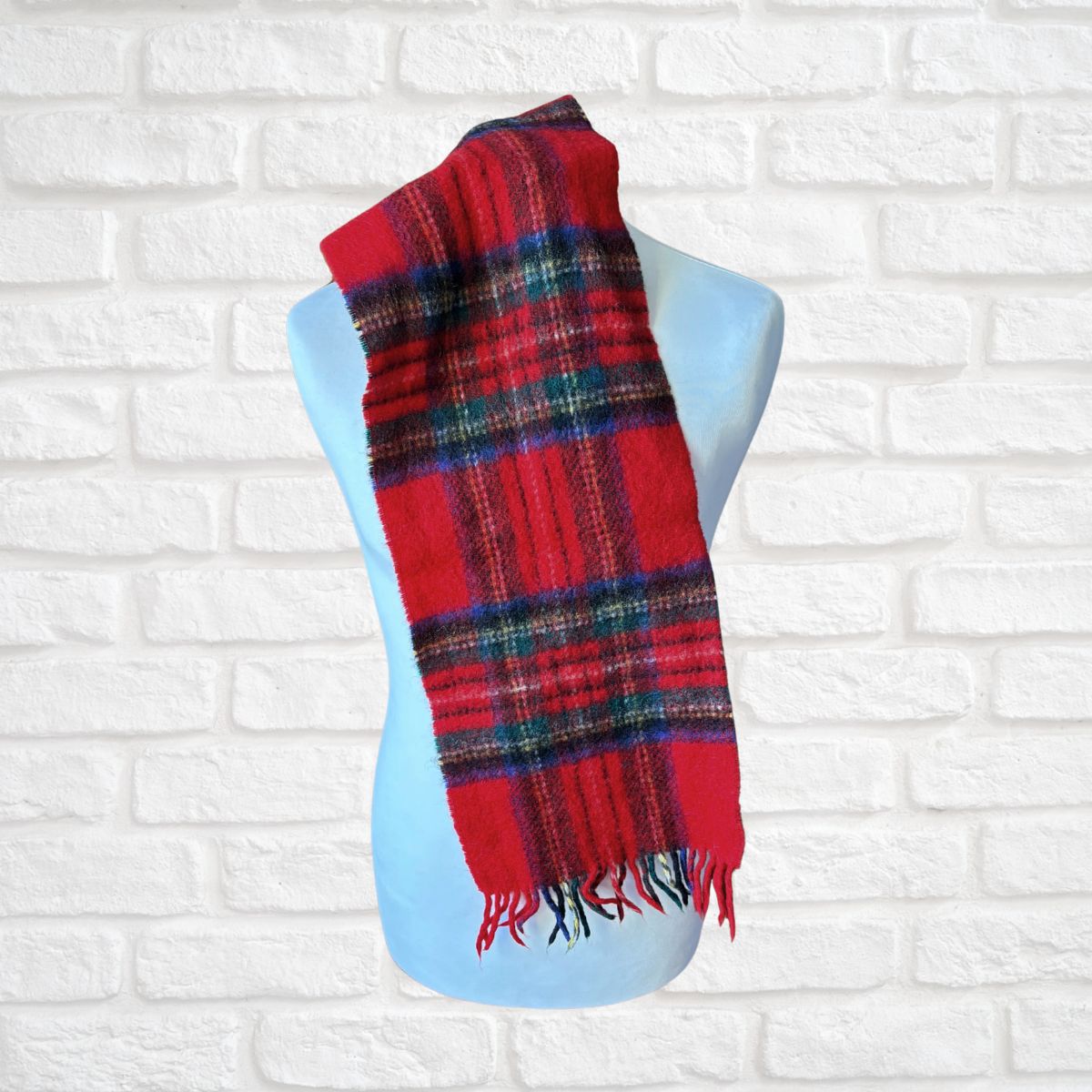 Red plaid scarf on a mannequin against a white brick wall background