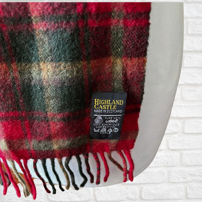 Plaid scarf with a visible label on a white brick wall background