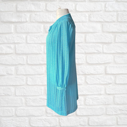 A turquoise blue ribbed long -sleeve cardigan displayed on a mannequin torso against a white brick wall background.