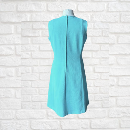 Turquoise dress on a mannequin against a white brick wall background