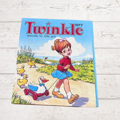 A vintage 1977 Twinkle magazine for girls, featuring a colorful illustration of a girl walking with ducks, displayed on a light-colored wooden background.