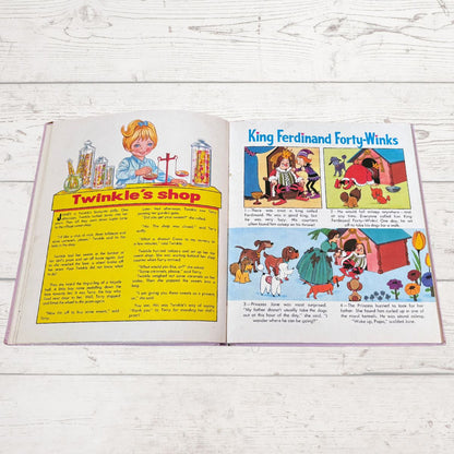 An open vintage children's book spread laid flat on a white wood surface. The left page shows a yellow 'Twinkle's shop' illustration with text below, and the right page shows a colorful comic-style story titled 'King Ferdinand Forty-Winks' with multiple illustrated panels.