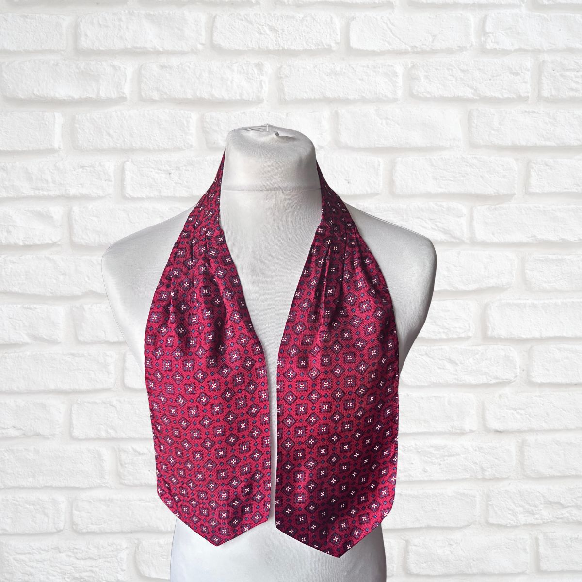 Red patterned cravat on a mannequin against a white brick wall background