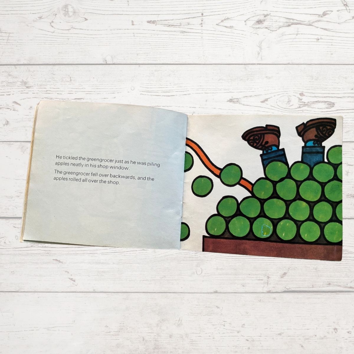 A picture of a pile of apples with some legs sticking out