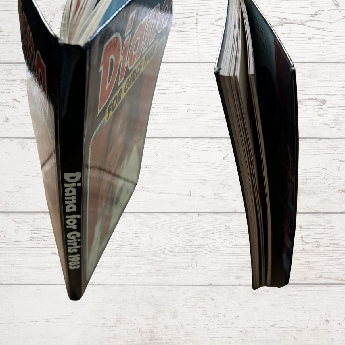 Open book showing the spine and corners with 'Diana' branding on a light wooden surface