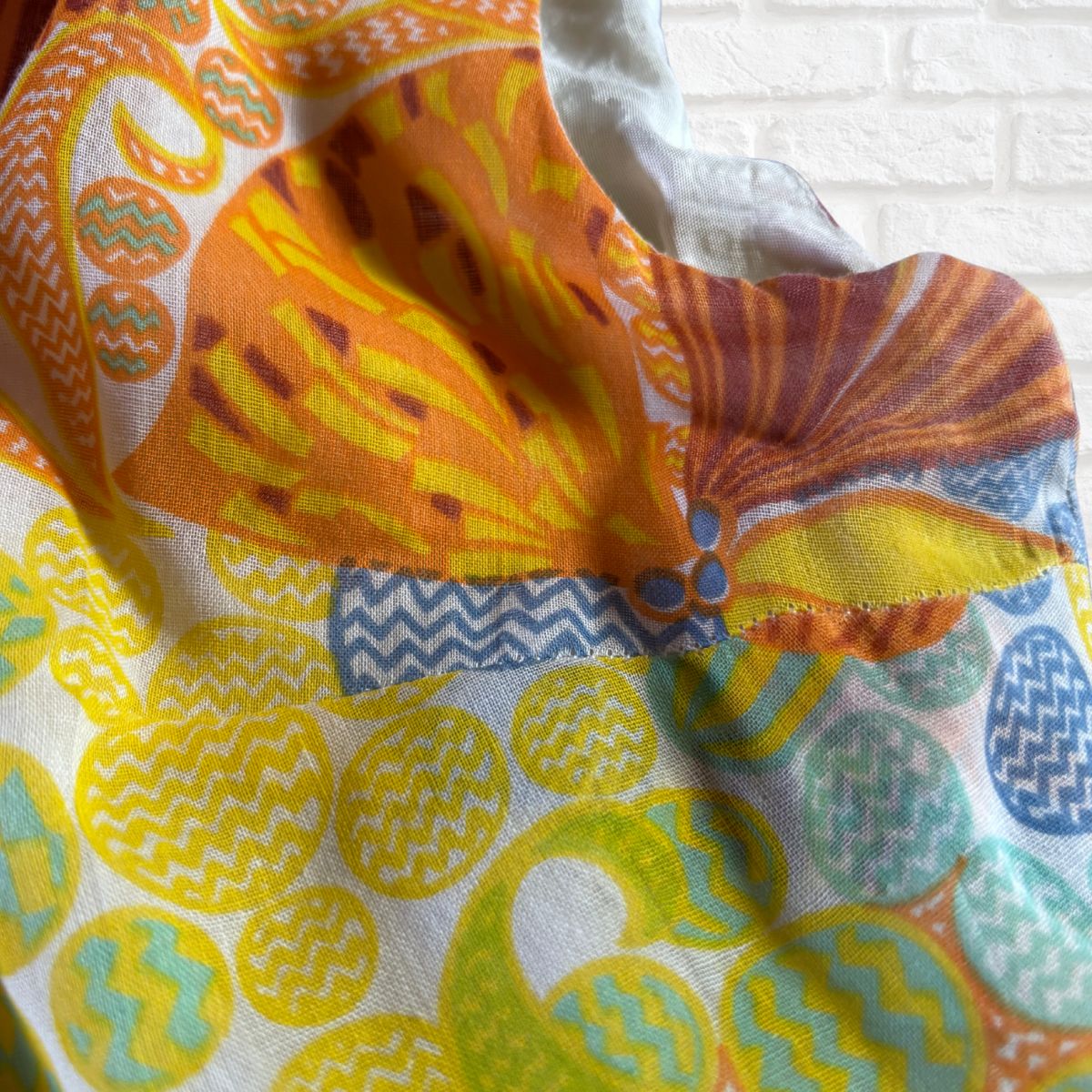 Colorful fabric with geometric patterns on a white brick wall background