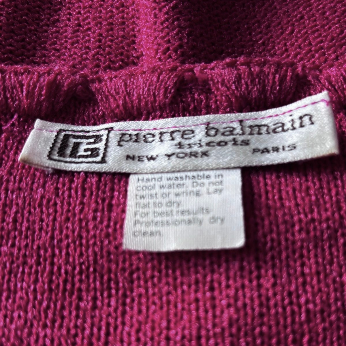 Pierre Balmain tricots label on pink fabric background