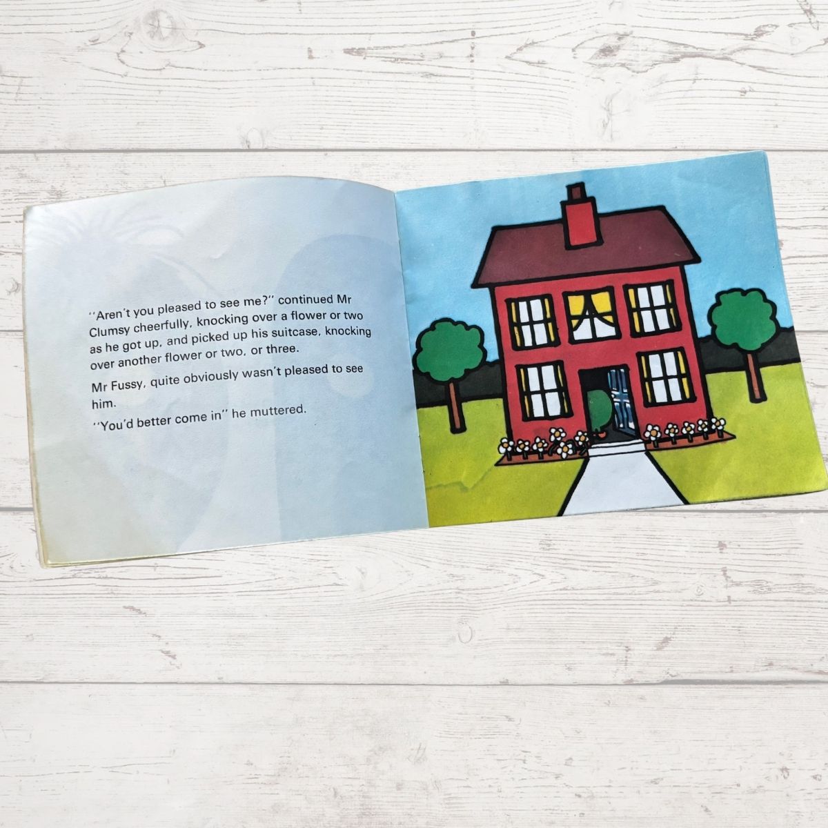Open book with a colorful illustration of a house on a wooden surface