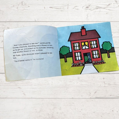 Open book with a colorful illustration of a house on a wooden surface