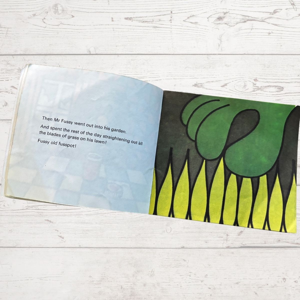 Open book with a green grass illustration on a wooden surface