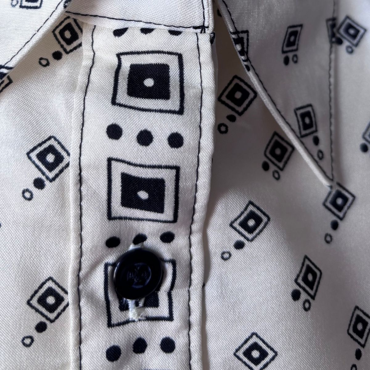 Cream and black geometric print 70s shirt, front placket close up on a white background 