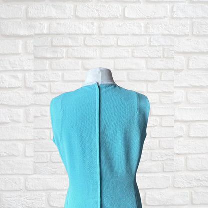 Turquoise dress  on a mannequin against a white brick wall background