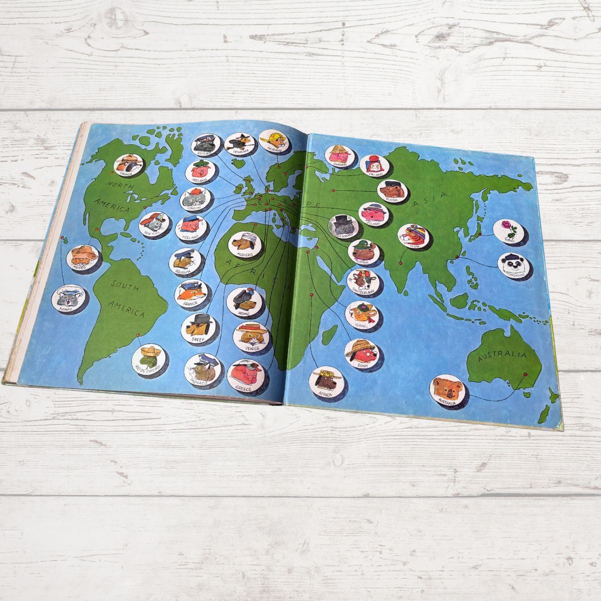 Open book with a world map and circular illustrations on a wooden surface
