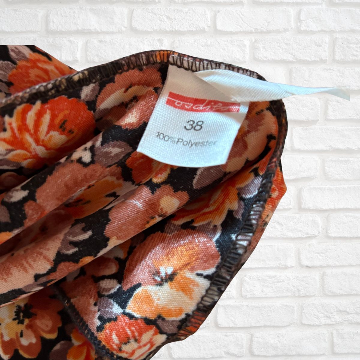 Floral patterned fabric with a tag on a white brick background