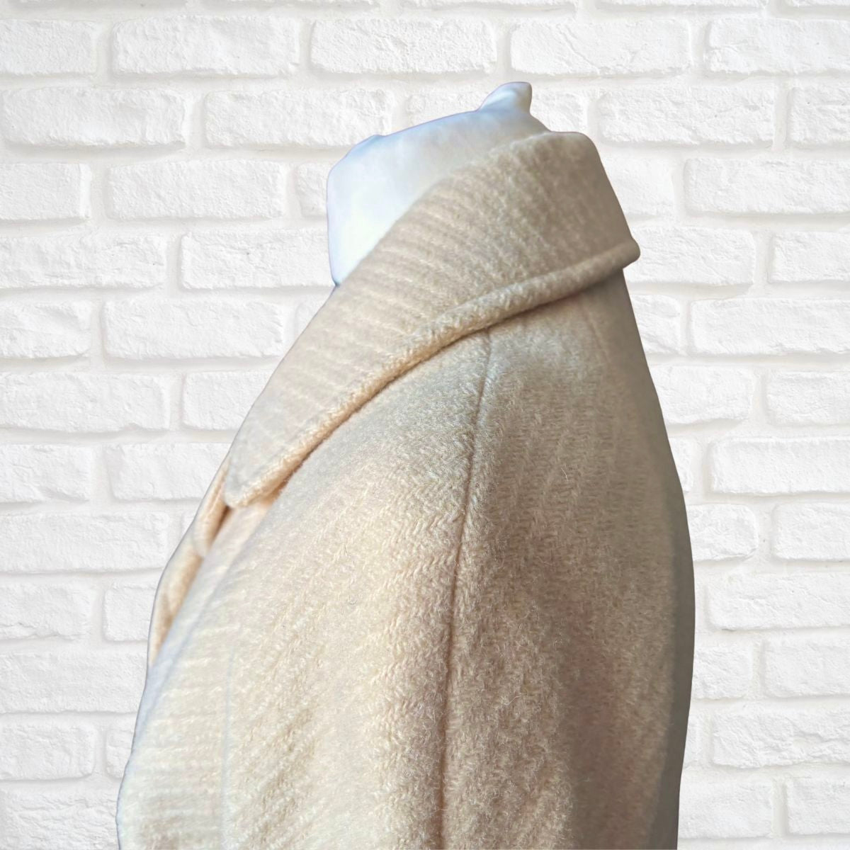 Neutral  coat on a mannequin against a white brick wall background