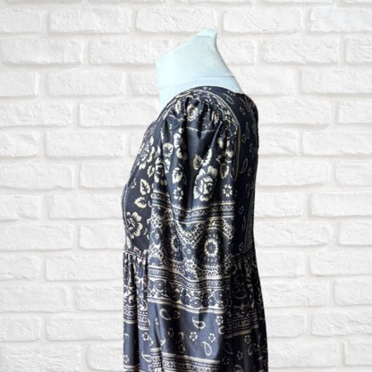 Black patterned dress on a mannequin against a white brick wall background
