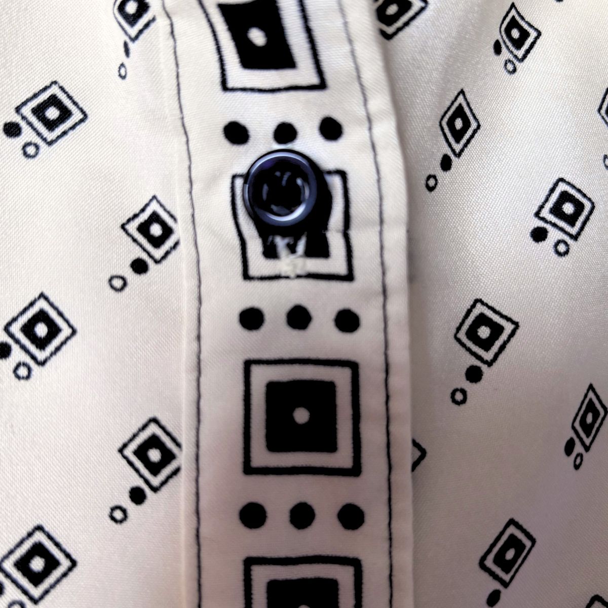 Cream and black geometric print 70s shirt, front placket close up on a white background 